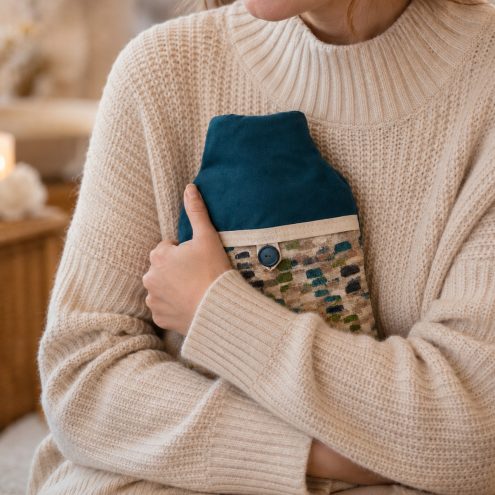 model holding blue green hot water bottle